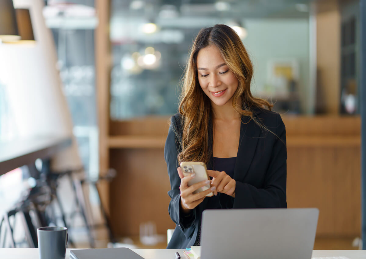 Frau schaut im Büro auf ihr Handy