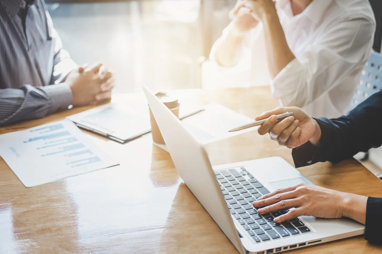 Team im Büro bei einer Besprechung mit Laptop zur digitalen Zusammenarbeit, Planung und Abstimmung von Arbeitsprozessen